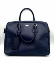 A Prada Saffiano Briefcase. Navy blue textured leather exterior. Prada logo badge. Name tag. Quality