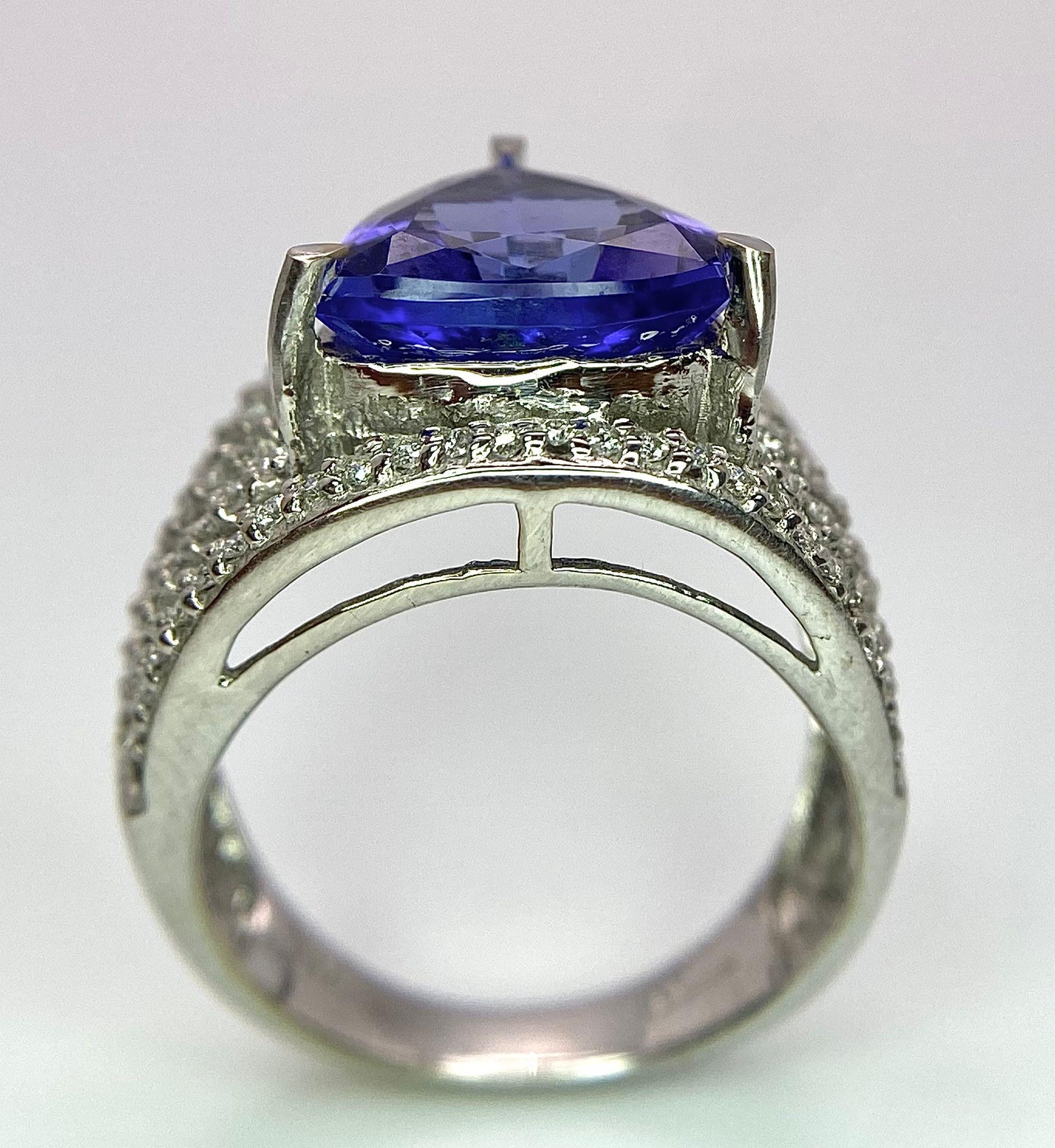 An 18K White Gold, Tanzanite and Diamond Ring. Trillion cut tanzanite with a five row diamond arch - Image 7 of 11