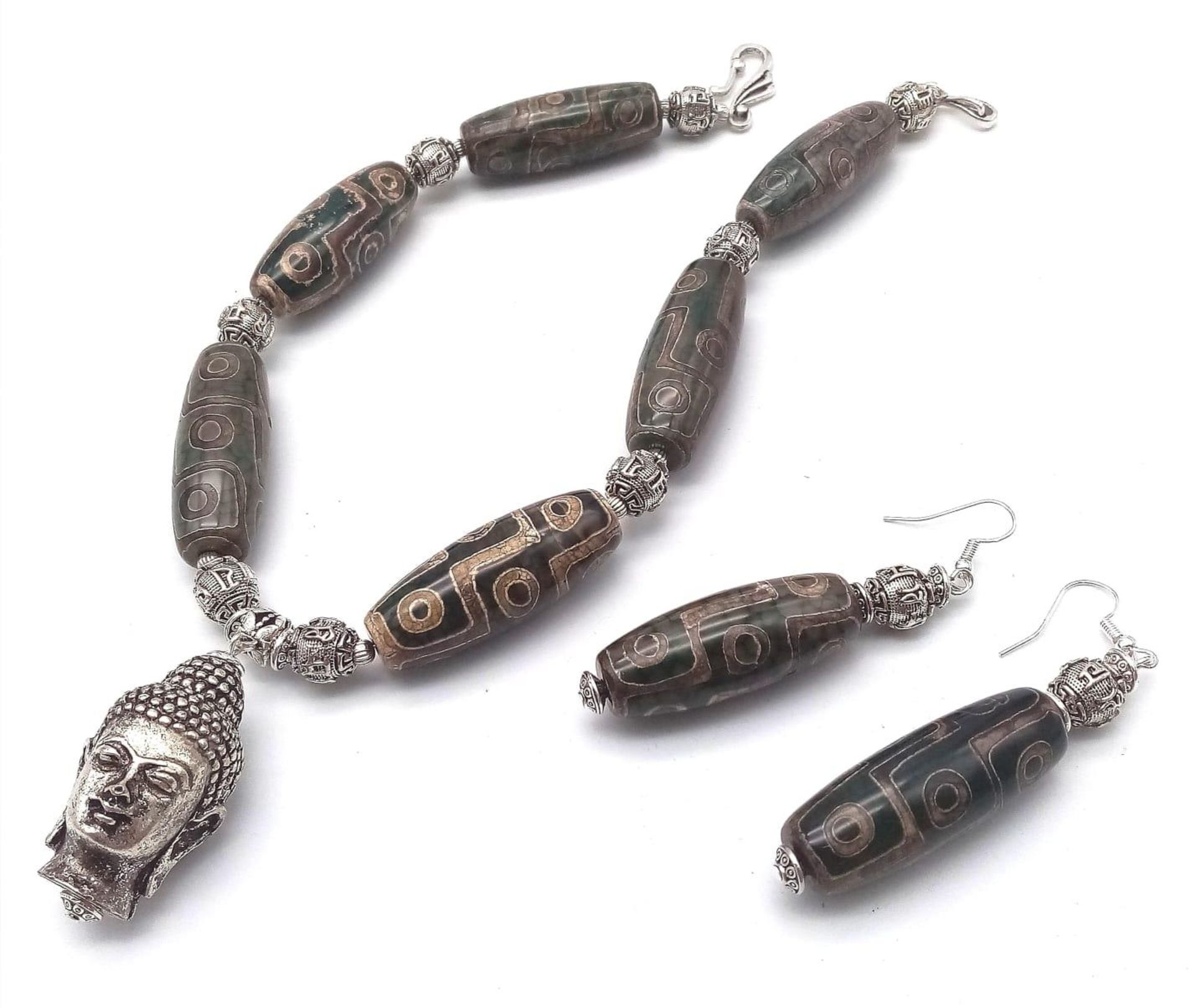 A Tibetan treasure: a nine eyed, large DZI beaded necklace and earrings set with a young Buddha head