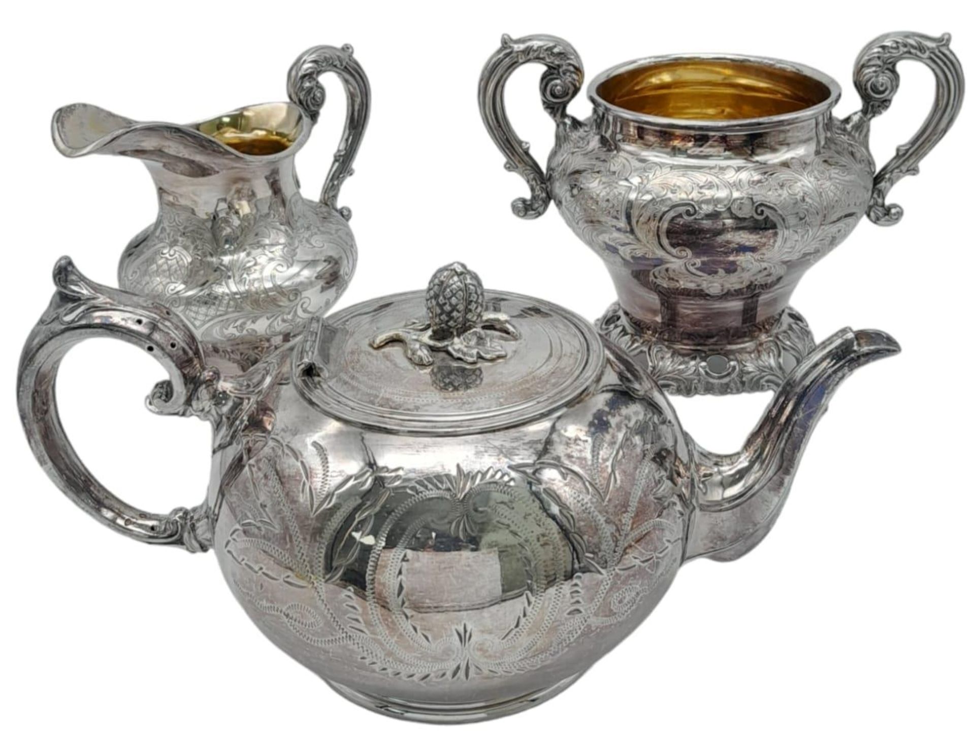 A Three-Piece Antique Silver Plated Tea Set. Includes a teapot, creamer and sugar bowl - with gilded