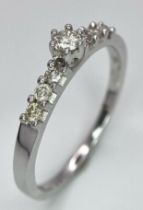 A 9K White Gold Diamond Ring. A tinted central cut round diamond with diamond accents on