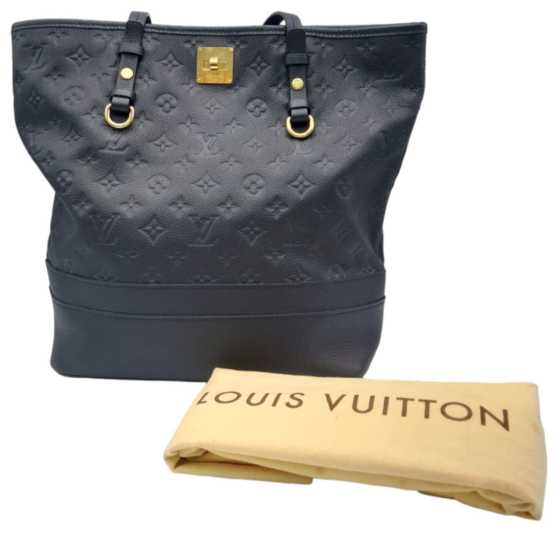 A Louis Vuitton Monogram Empreinte PM Tote Bag. Navy blue exterior with gold tone hardware. Spacious