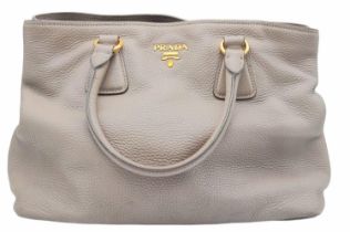 A Prada Vitello Daino Tote Pomice Bag. Textured leather exterior with gold-tone hardware. Decorative