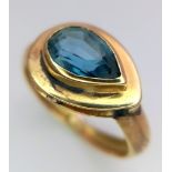 An 18K Yellow Gold Blue Gemstone (possibly topaz) Ring. Pear shaped stone set within a raised