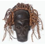 An antique Maasai wooden mask of a young warrior with red long “hair”. In very good condition for