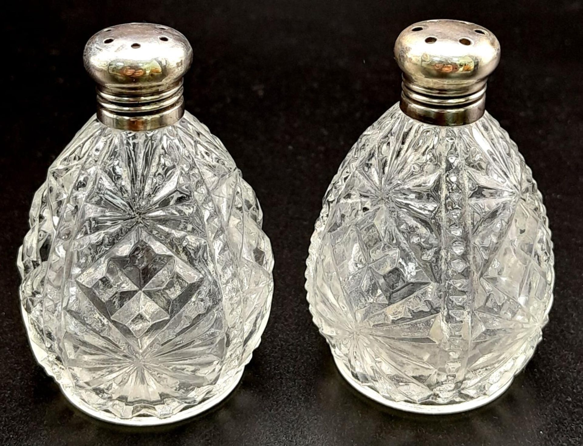 A PAIR OF VINTAGE SILVER TOPPED CUT GLASS SALT AND PEPPER POTS . 6cms IN HEIGHT 92.4gms