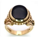A GENTS 9K GOLD REGAL LOOKING SIGNET RING WITH BLACK ONYX CENTRE STONE AND ORNATE SHOULDER WORK.