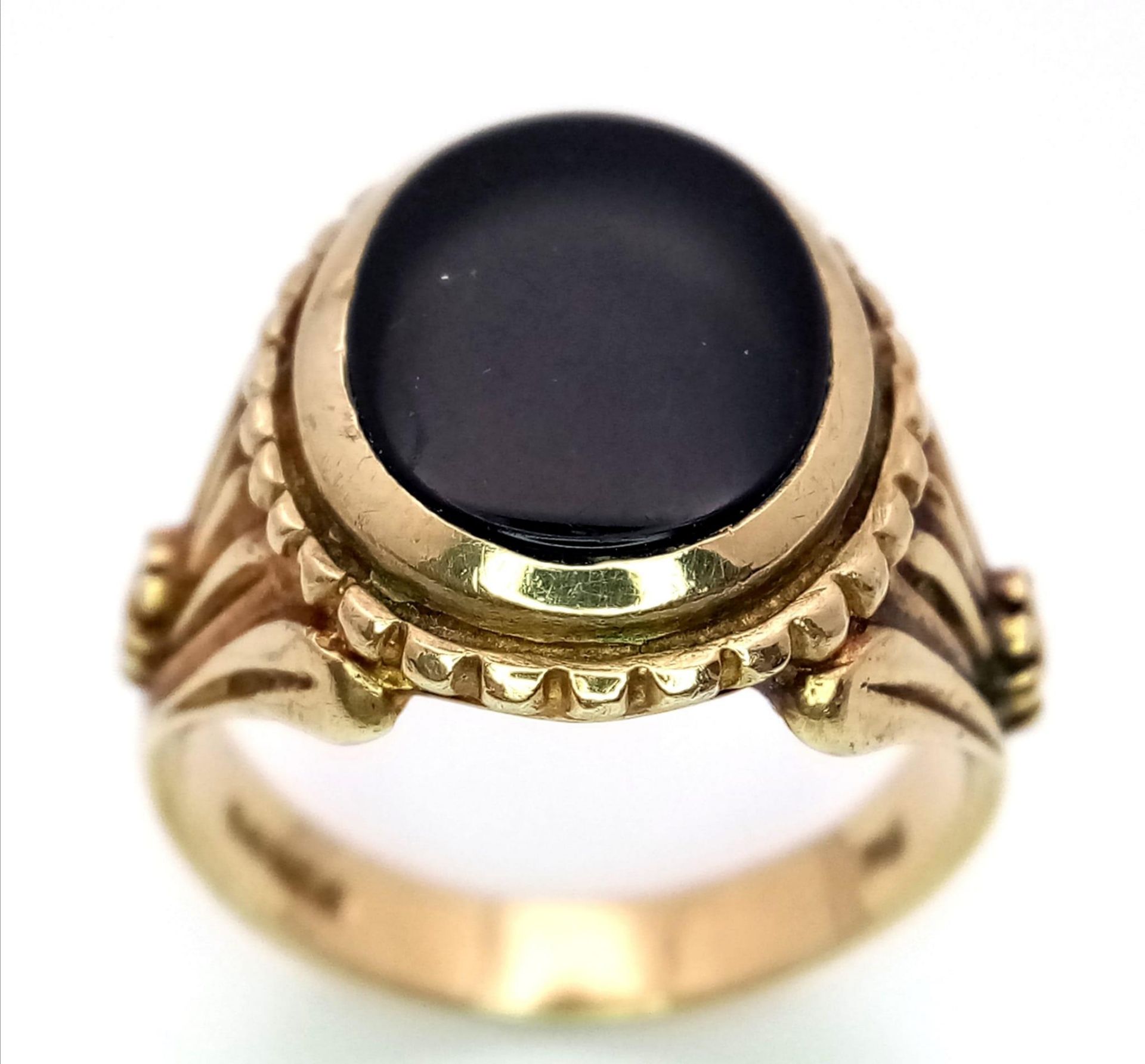 A GENTS 9K GOLD REGAL LOOKING SIGNET RING WITH BLACK ONYX CENTRE STONE AND ORNATE SHOULDER WORK.