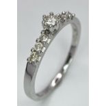 A 9K White Gold Diamond Ring. A tinted central cut round diamond with diamond accents on