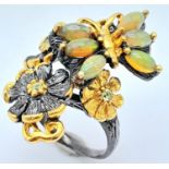 An Edwardian sterling silver ring with a naturalistic motif carrying six opal cabochons with a