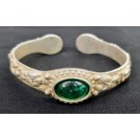A vintage Chinese silver bangle with green Peking Glass cabochons and eight old sage men adorning
