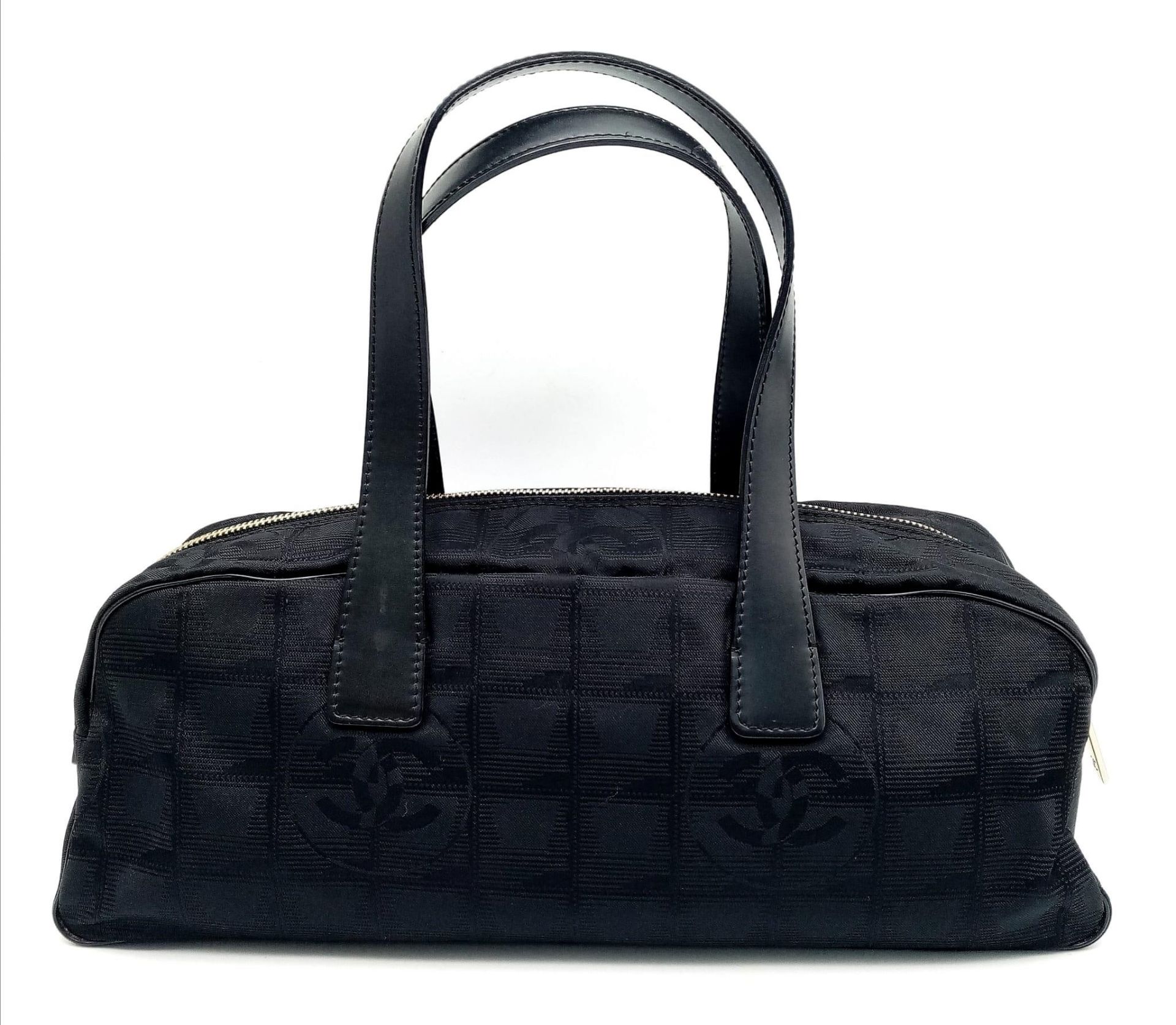 A Chanel Black Travel Line Bag. Canvas exterior with leather straps, four protective base studs