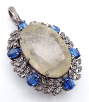 A 26ct Rutilated Quartz Gemstone Pendant with 2.50ctw Kyanite Surround. Set in 925 silver. 4.5cm.