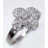 A 18K WHITE GOLD CLOVER SHAPED 0.20CT DIAMOND SET RING. TOTAL WEIGHT 4.1G. SIZE M