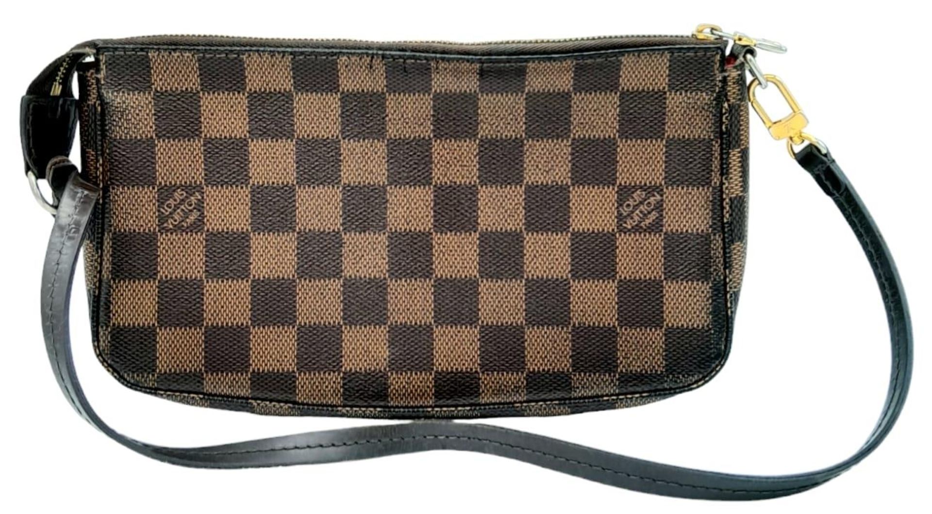 A Louis Vuitton Damier Ebene Pochette with Leather Exterior. Top Zip Closure. Red Fabric Lining with