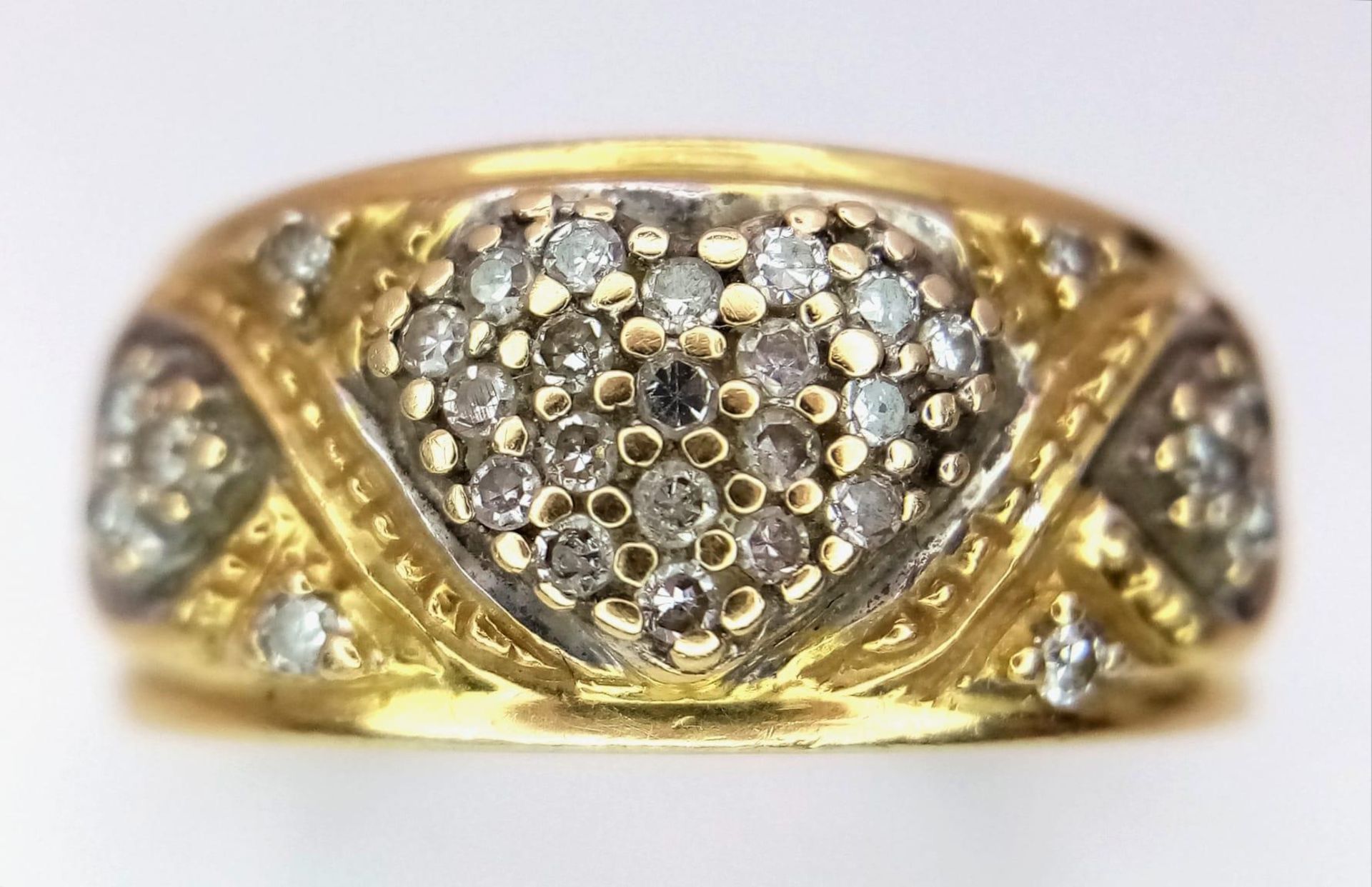 A Vintage 18K Yellow Gold Diamond Decorative Heart Ring. A central pave diamond heart with scrolls