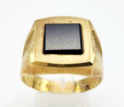 A GENTS 9K GOLD SIGNET RING WITH SQUARE BLACK ONYX CENTRE STONE AND BARKED EFFECT ON SHOULDERS . 6.