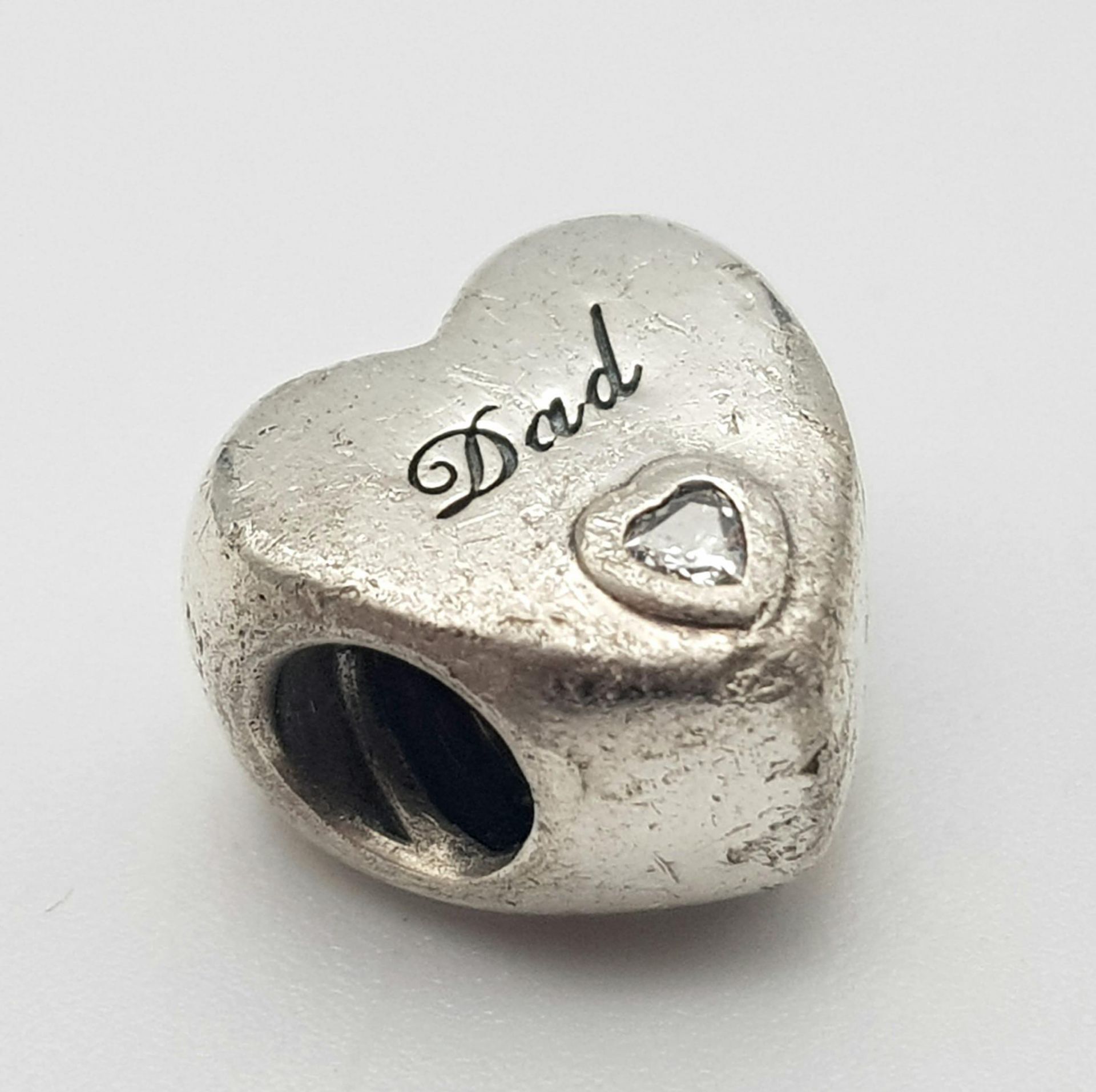 A PANDORA STERLING SILVER HEART SHAPED STONE SET CHARM, ENGRAVED WITH THE WORD "DAD" 3.9G ref: SC