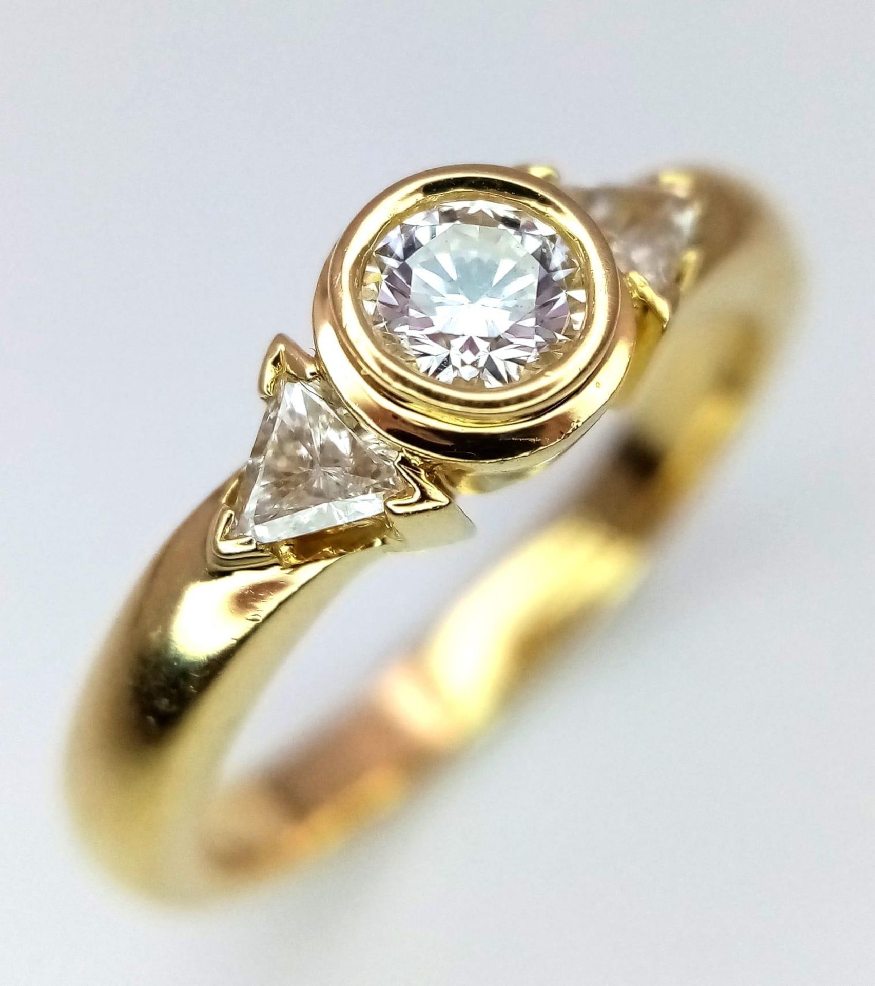 An 18K Yellow Gold Diamond Ring. Central round cut diamond with trillion cut diamond accents. Size - Bild 2 aus 6