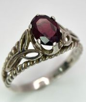A vintage sterling silver faceted Garnet solitaire ring with further decoration on shoulder. Come