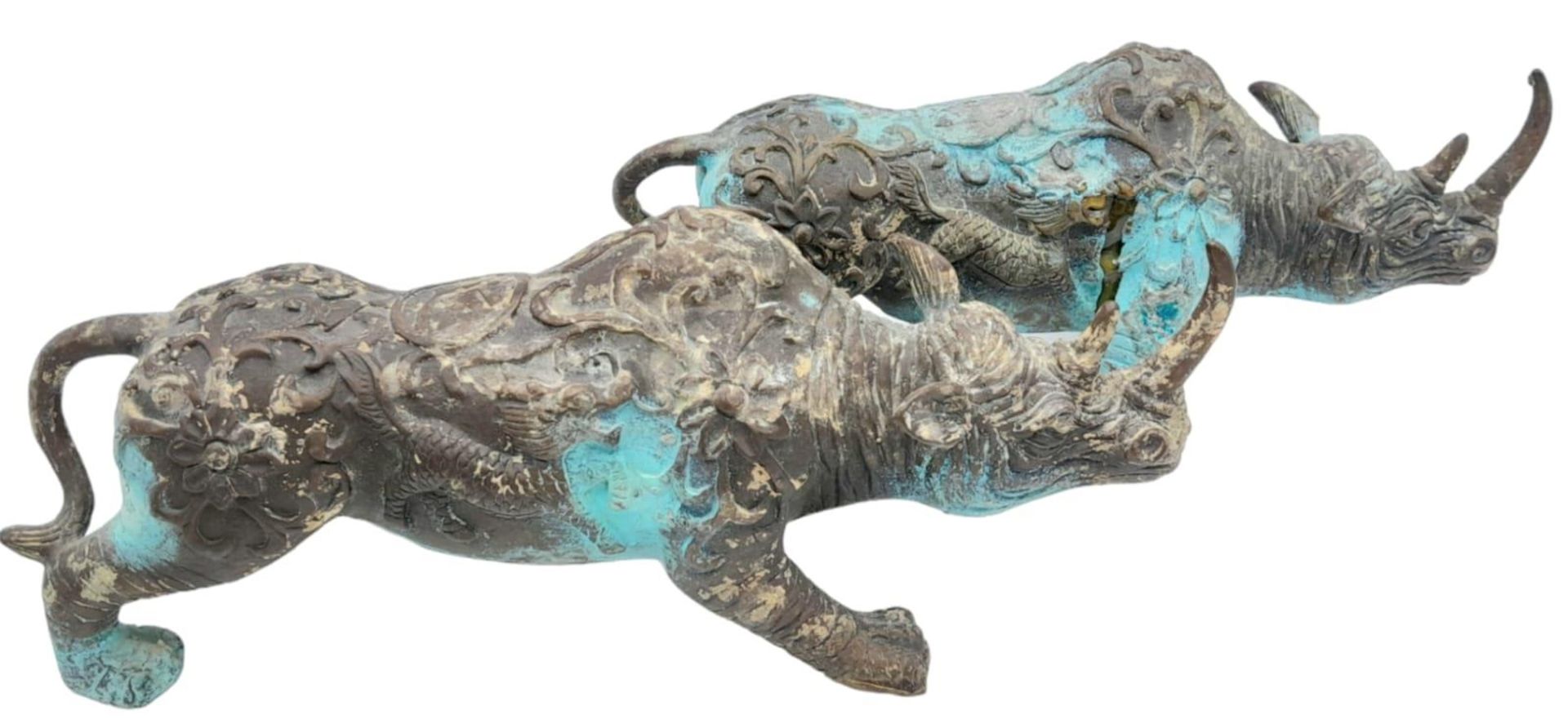 A PAIR OF VERY EARLY ANTIQUE CHINESE BRONZE WARE CEREMONIAL RHINOCEROSES WITH DRAGON ON FLANKS,