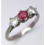 A Vintage Platinum Diamond and Ruby Ring. A central ruby with two brilliant round cut diamonds. Size