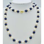 A Lapis Lazuli and Cultured Pearl Necklace. Gilded spacers and clasp. 68cm necklace length.