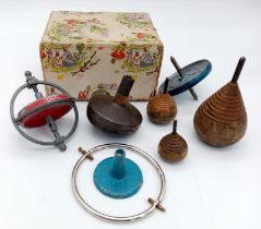 A collection of six vintage spinning tops. There are three wooden ones, one brass one and two