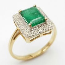 A 9K GOLD RING WITH 2.5ct NATURAL EMERALD SURROUNDED BY DIAMONDS. 3.8gms size O