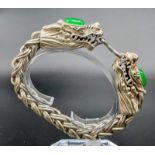 A Vintage, Chinese silver, double headed dragon bracelet with two green jade cabochons. In a