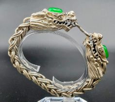 A Vintage, Chinese silver, double headed dragon bracelet with two green jade cabochons. In a