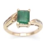 A 1ct EMERALD IN A 9K GOLD RING WITH WHITE SAPPHIRE SHOULDERS . 2.6gms size O