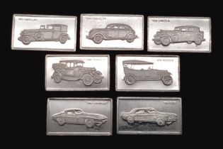 A SELECTION OF 7 STERLING SILVER AMERICAN CAR MANUFACTURERS MINI PLAQUES WITH LOGO AND CARS AND