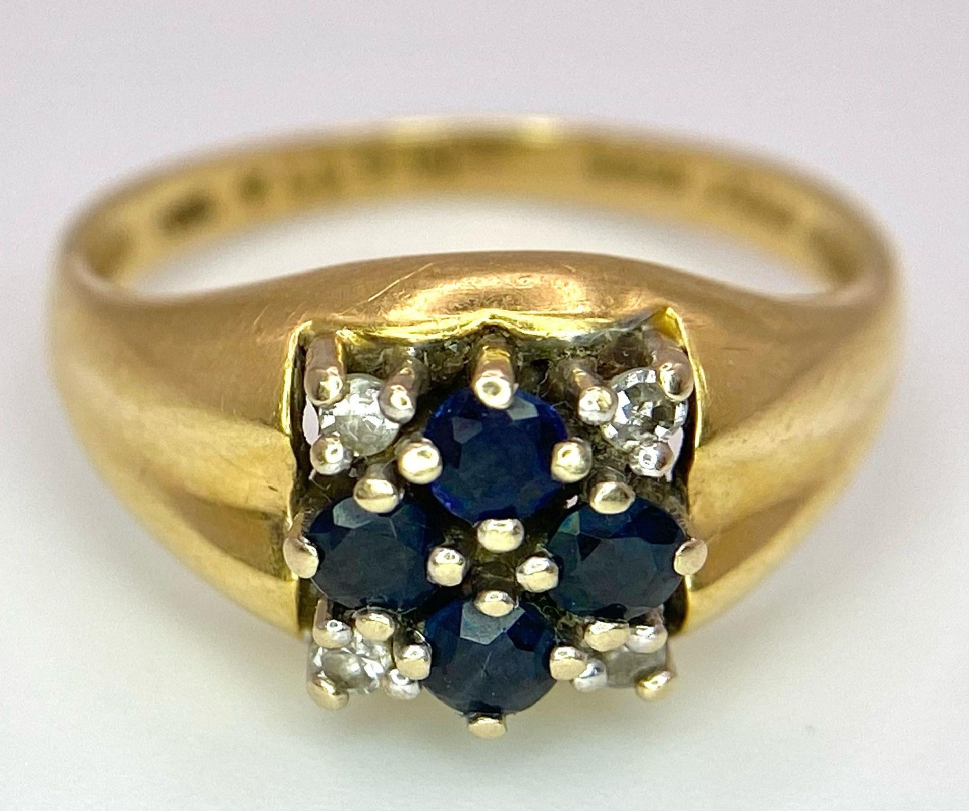 An 18K Yellow Gold Sapphire and Diamond Ring. A cross of four central sapphires with a diamond in