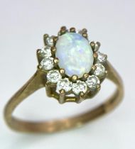 A 9K Yellow Gold, Opal and Diamond Ring. Central colour-play opal with diamond halo. Size O. 2.27g