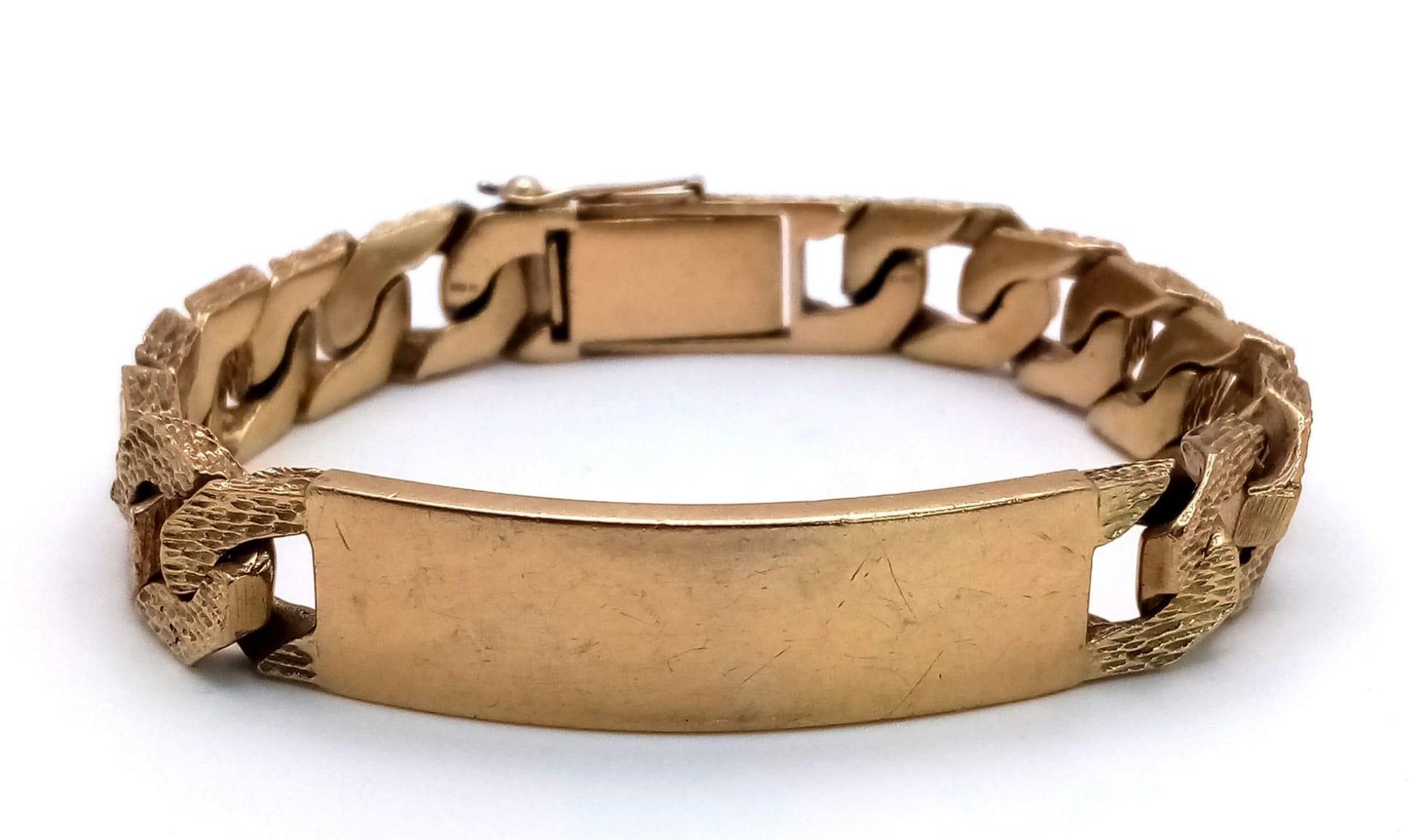 A CHUNKY 9K GOLD I.D. BRACELET WITH BARK EFFECT LINKS AND SAFETY CHAIN . 59.2gms