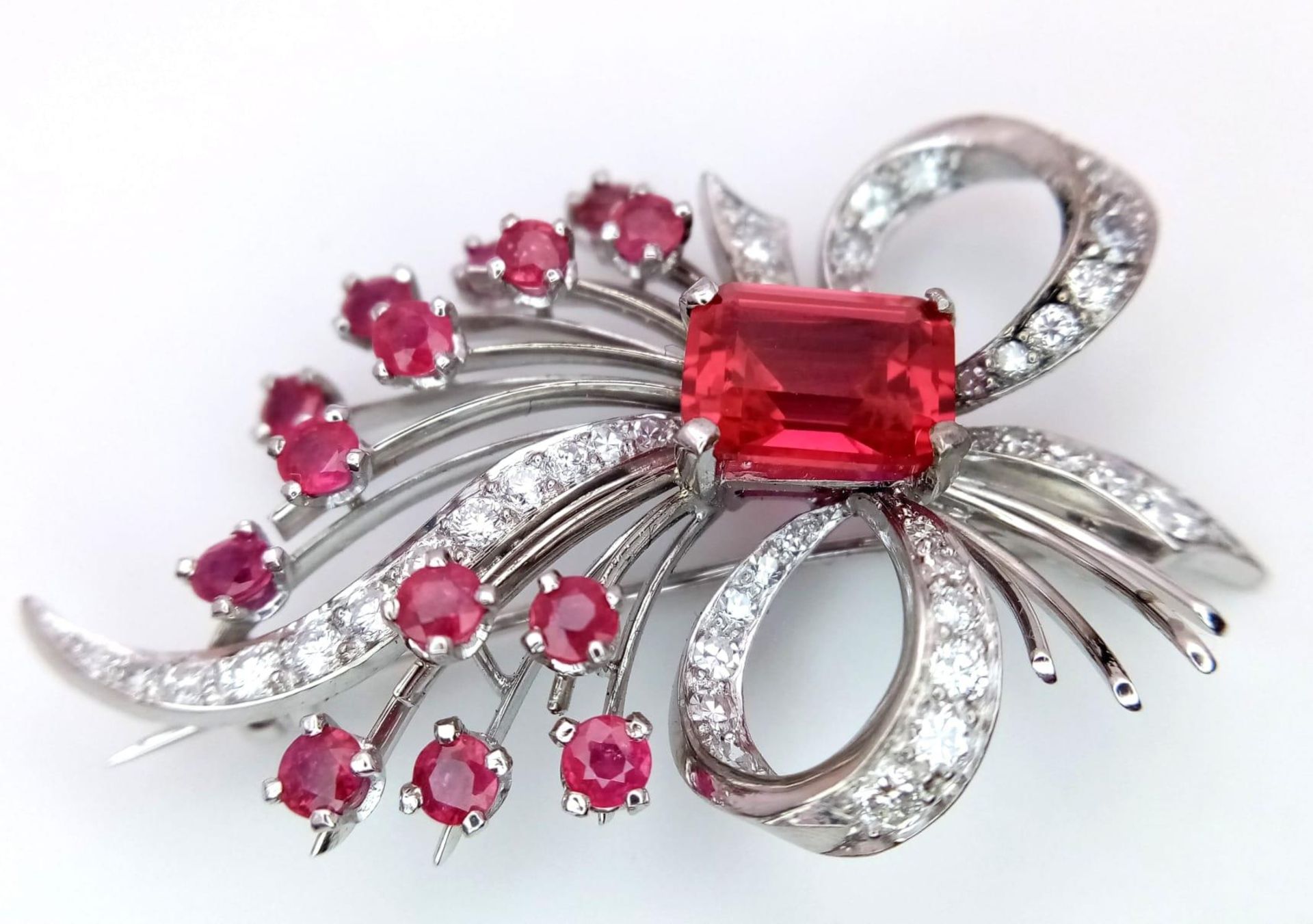 A STUNNING DIAMOND AND RUBY BROOCH SET IN PLATINUM , A MAJESTIC SPRAY OF RUBIES EMINATING FROM A