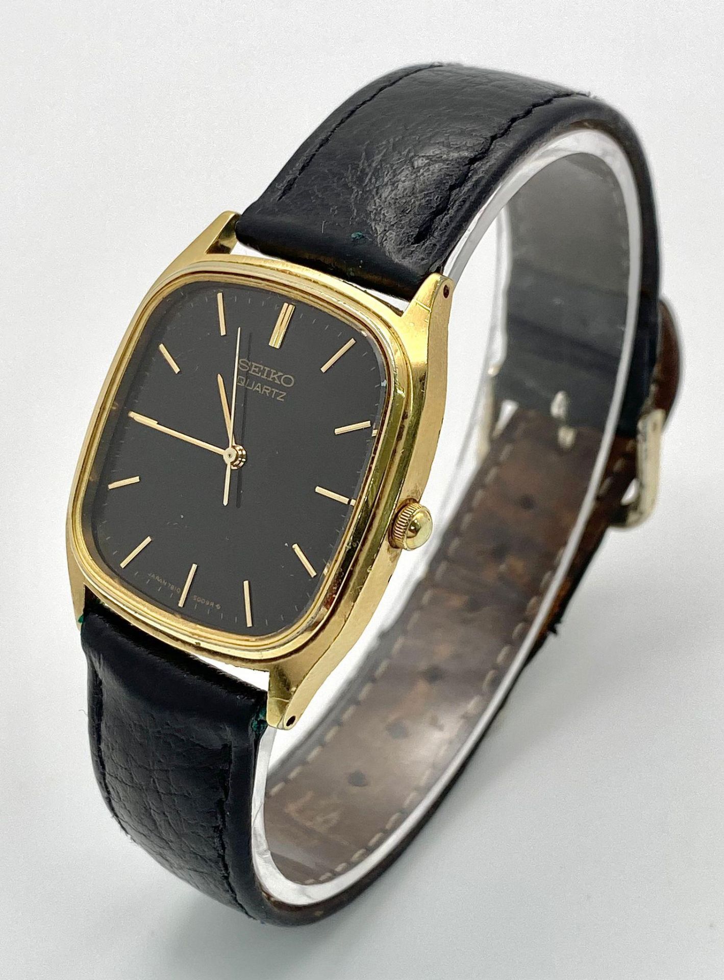 A gold plated, steel SEIKO watch, case: 32 x 29 mm, black dial with gold coloured hour marks and