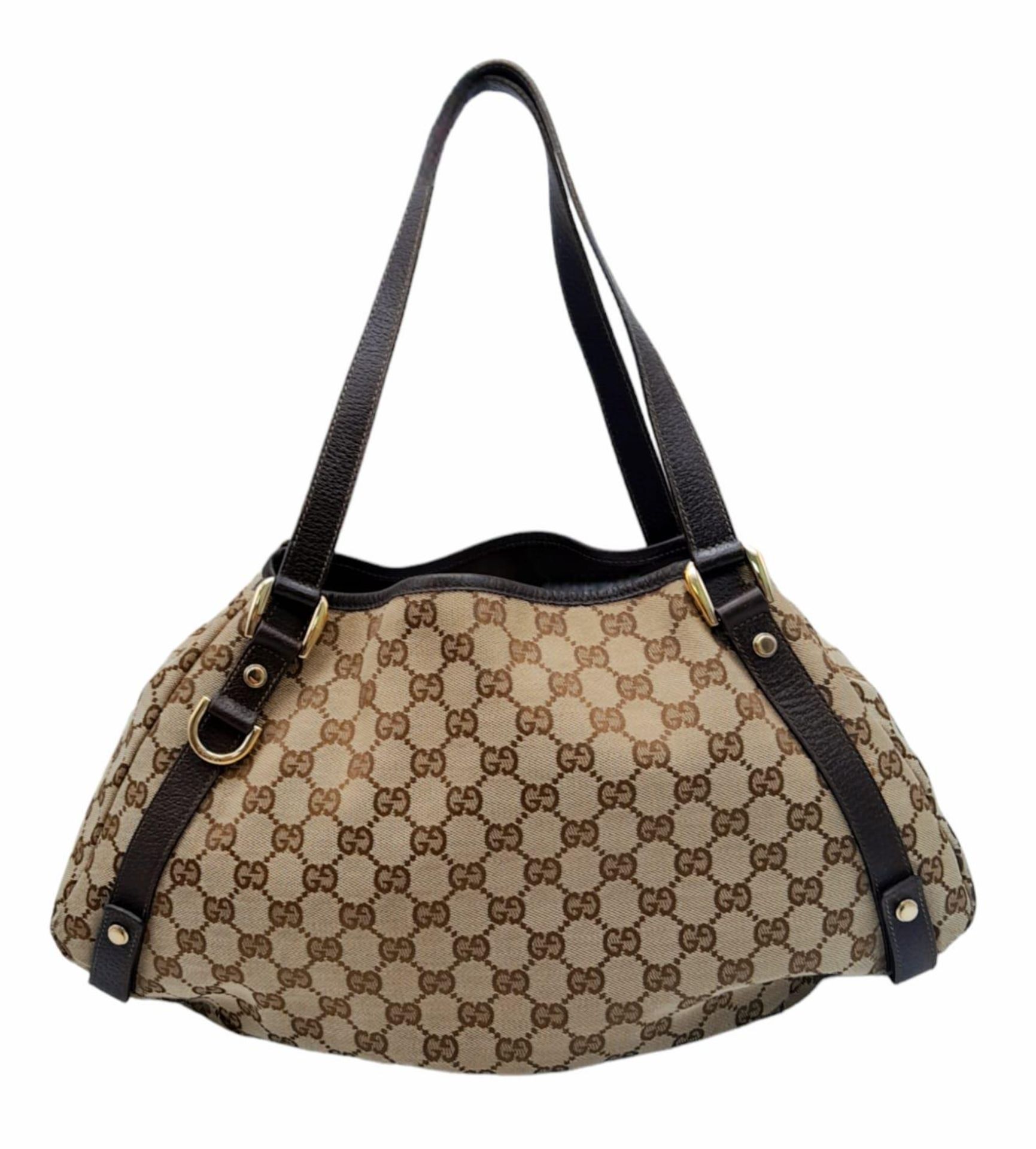 A Gucci Brown Monogram 'Abbey' Shoulder Bag. Canvas exterior with leather trim, gold-toned hardware,