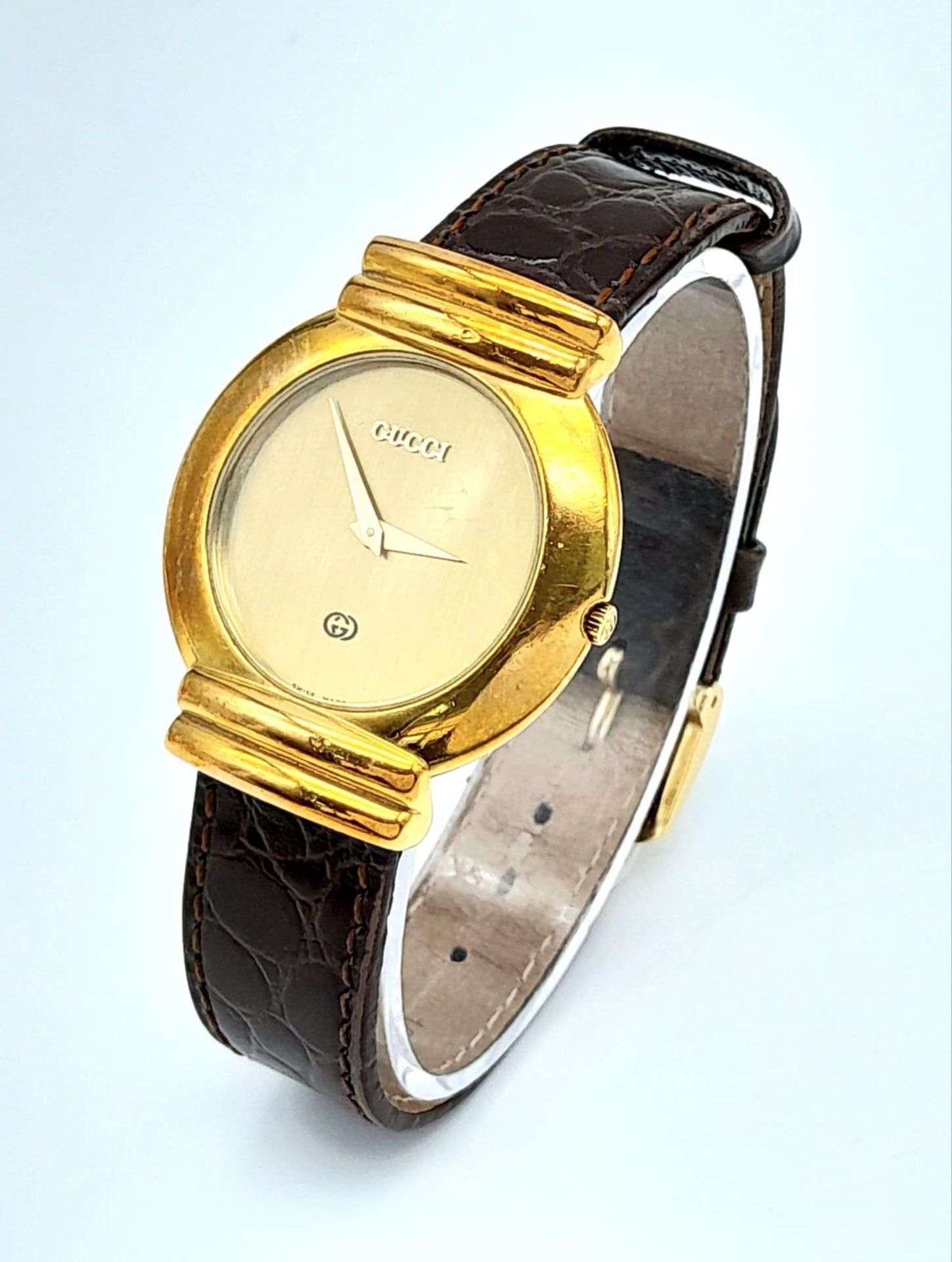 A gold plated GUCCI with crocodile skin strap, case: 33 mm, gold coloured dial and hands, Swiss made