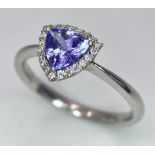 A 9K White Gold Tanzanite and Diamond Ring. Trillion cut tanzanite with a diamond surround. Size