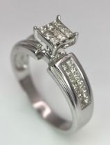 A 14K White Gold Diamond Ring. Nine small central squares with diamond squares on shoulders. 0.