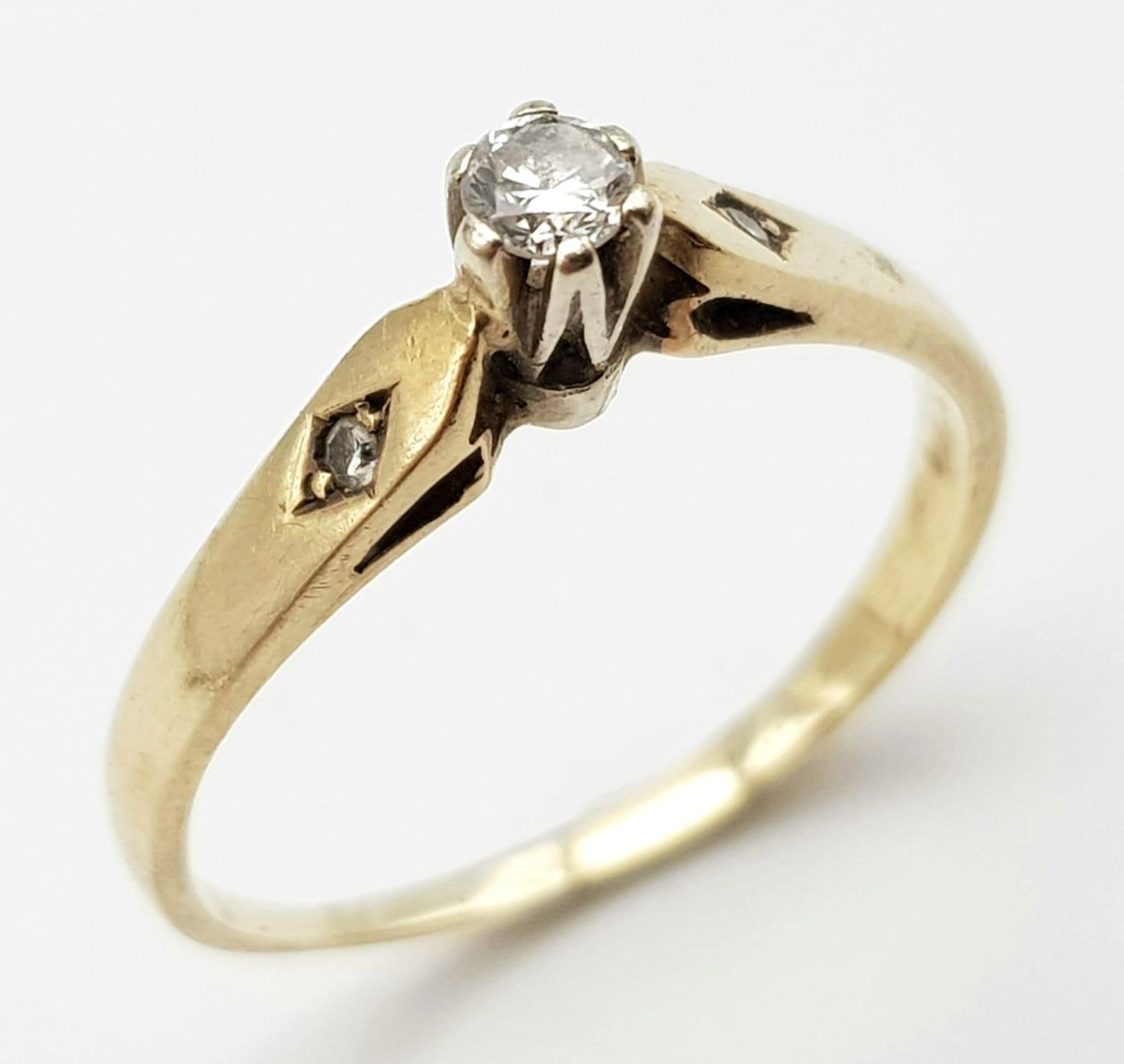 A 9K Yellow Gold Diamond Ring. 0.2ct central diamond with diamond accents. Size M 1/2. 1.52g total