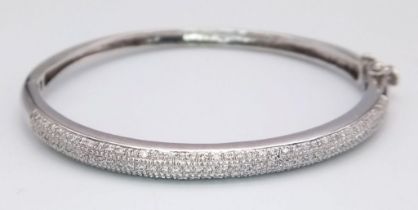 A PRETTY 9K WHITE GOLD DIAMOND SET BANGLE WITH APPROX 0.60CT DIAMONDS IN TOTAL, WITH SAFETY CATCH