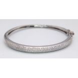 A PRETTY 9K WHITE GOLD DIAMOND SET BANGLE WITH APPROX 0.60CT DIAMONDS IN TOTAL, WITH SAFETY CATCH
