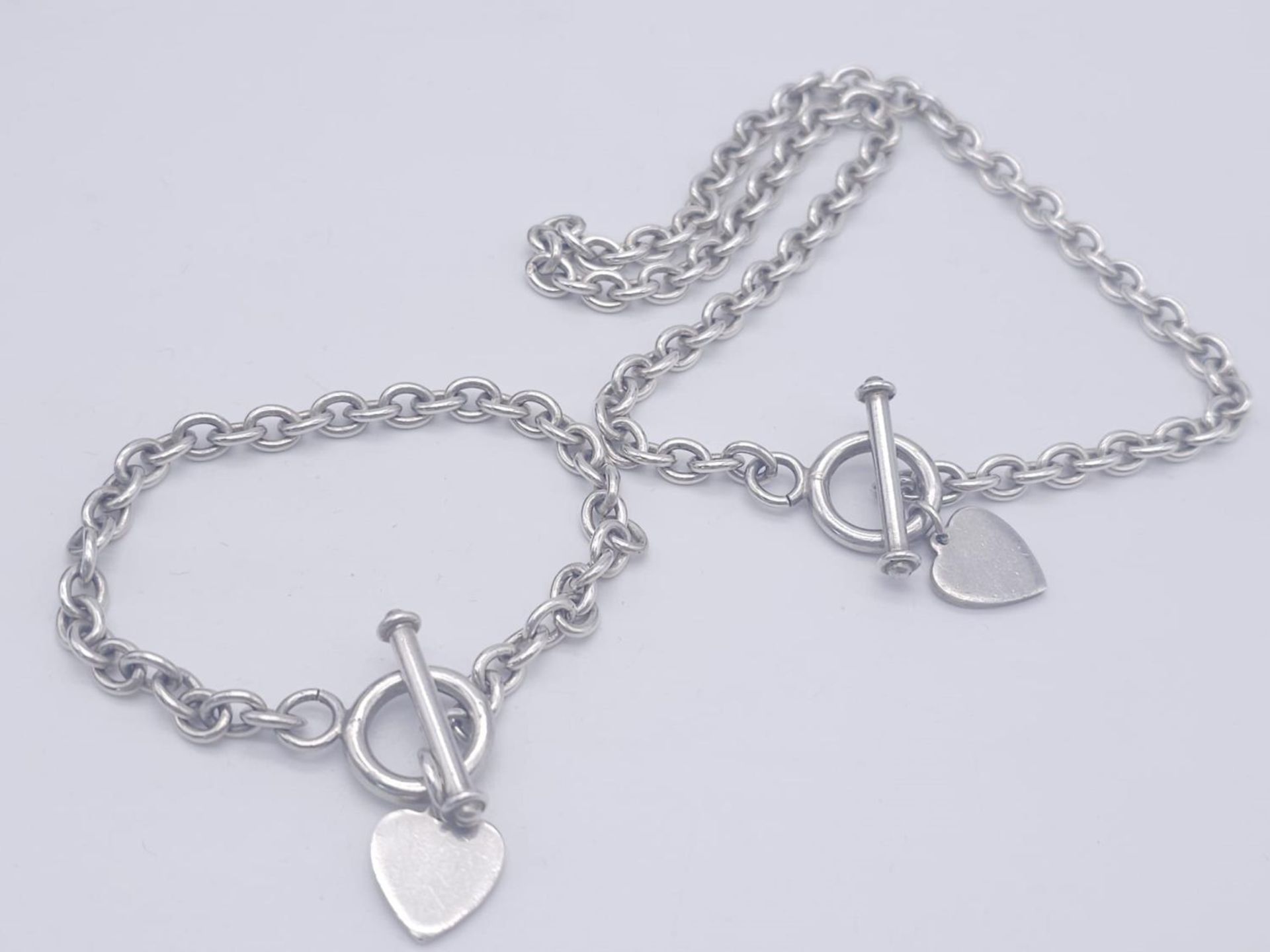 A Sterling silver T-bar heart necklace with matching 20cm bracelet. 54.3g total weight.