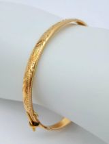 A 9 K yellow gold bangle with a decorative engraving on top half, weight: 12.4
