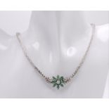 An 18K White Gold Diamond and Emerald Necklace. A scale pattern necklace that leads to an emerald