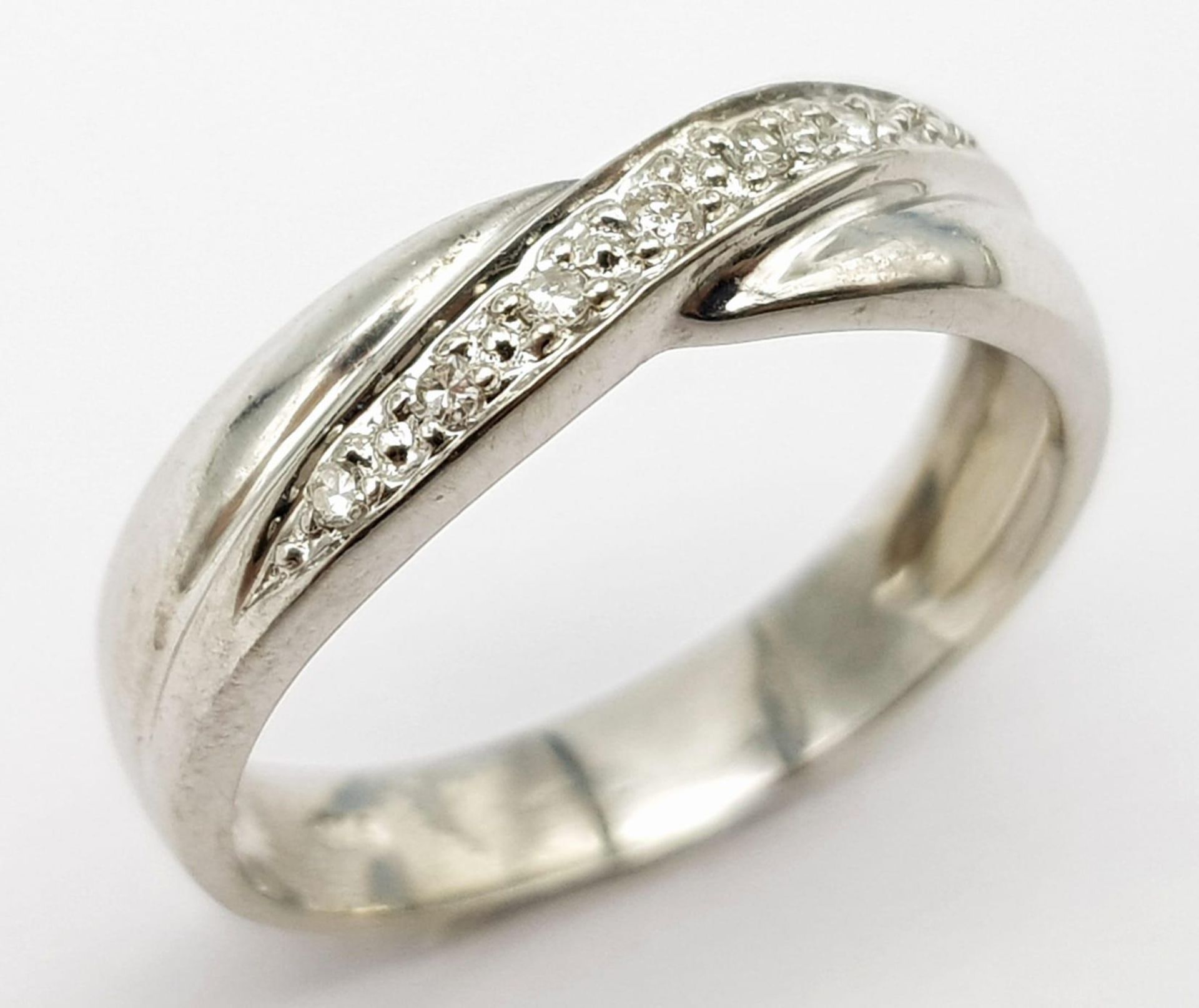 A 9K white Gold (tested) Diamond Twist Ring. 0.05ct diamond. Size K. 2.4g total weight.
