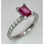 A very elegant platinum ring with an emerald cut ruby and diamonds (0.60 carats) on the crown and